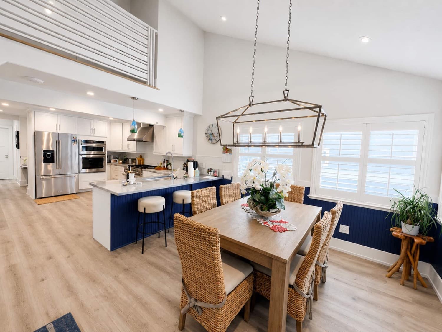 Bright coastal kitchen and dining space with island seating and vaulted ceilings
